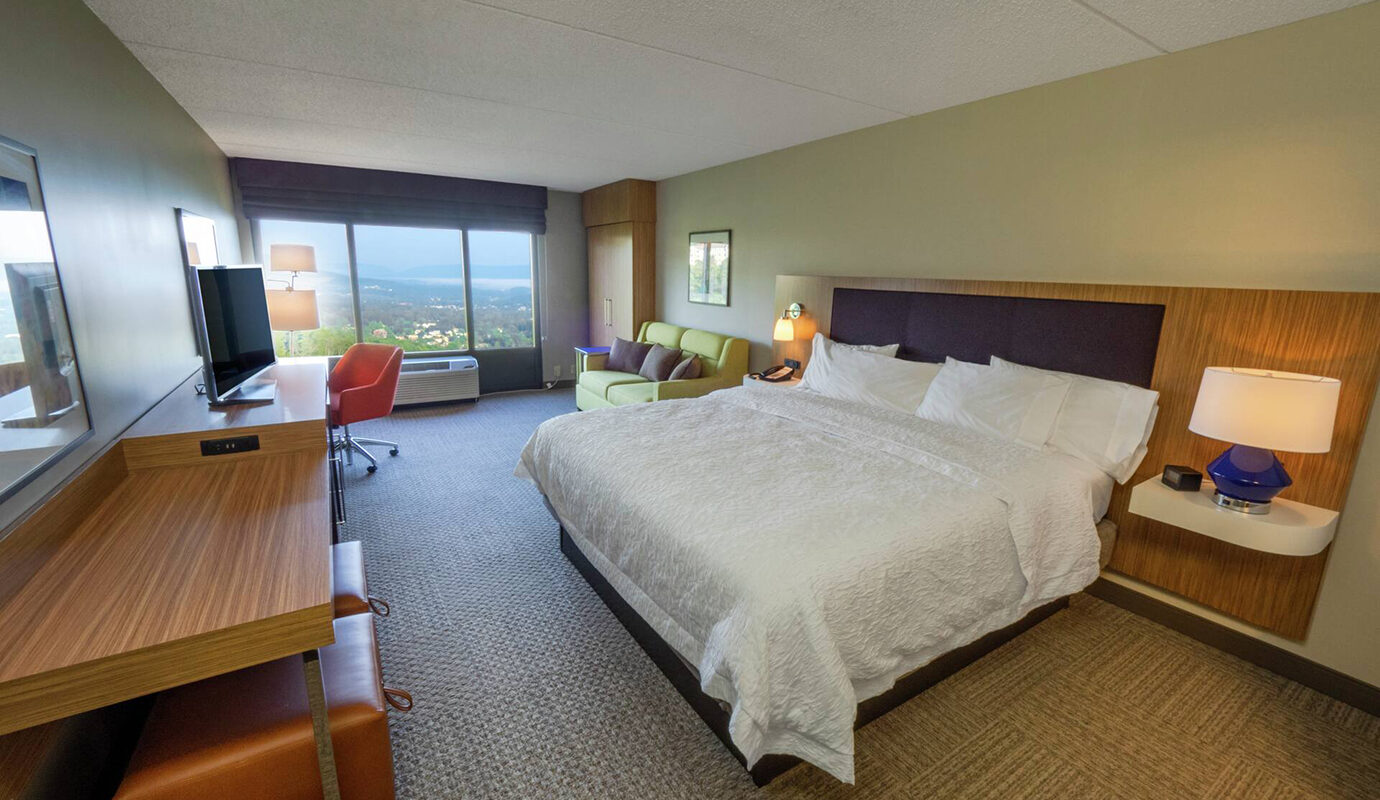 King size guest room with couch, tv, desk and dresser