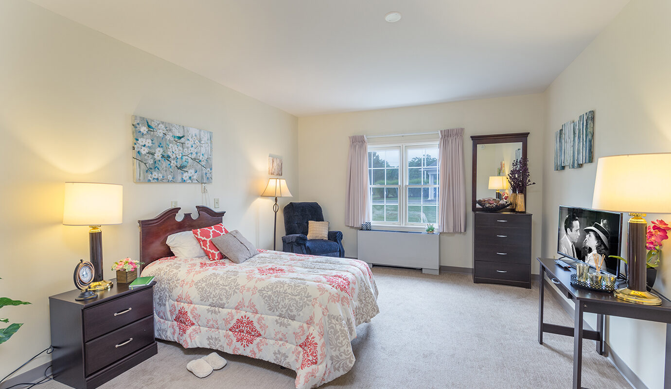 Bedroom with chair, dresser, TV and desk