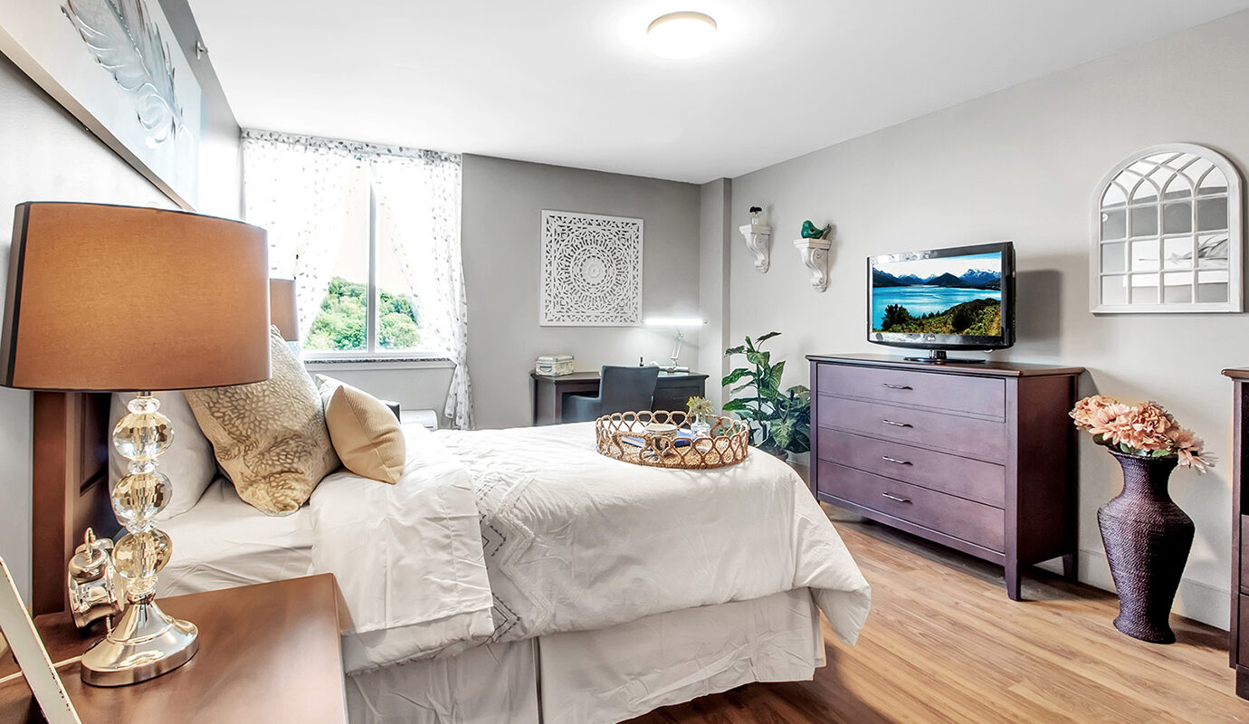 Decorated bedroom with bed, dresser, desk and tv