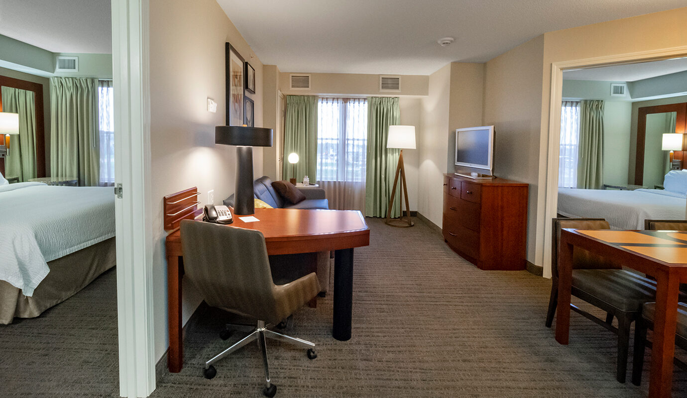 Guest room with king size bed, desk, table and chairs, dresser, TV, and couch.