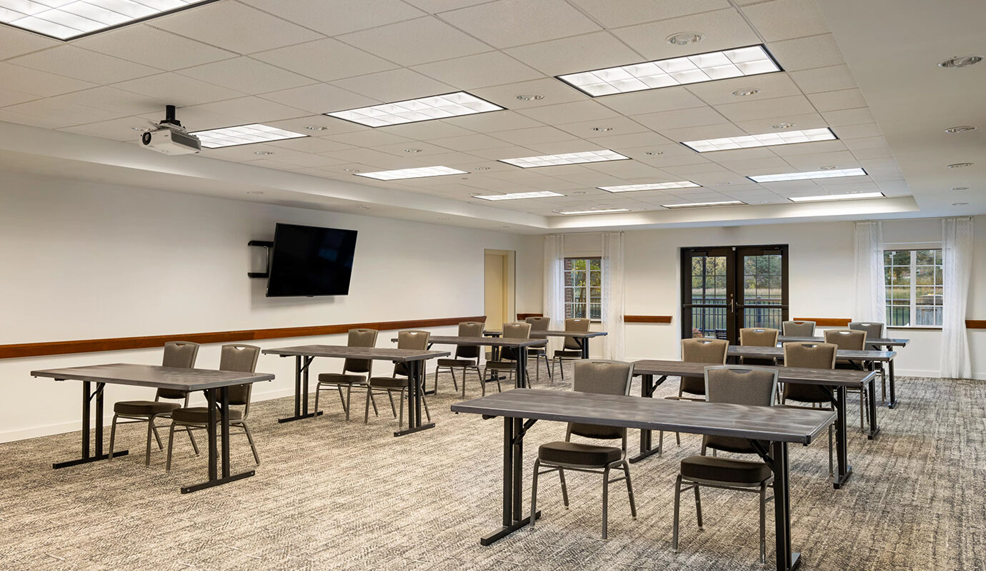 Conference room with several tables and chairs and a tv on the wall