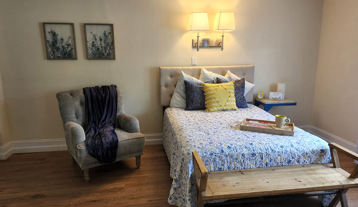 Cute bedroom with bed, chair, bench, and side table