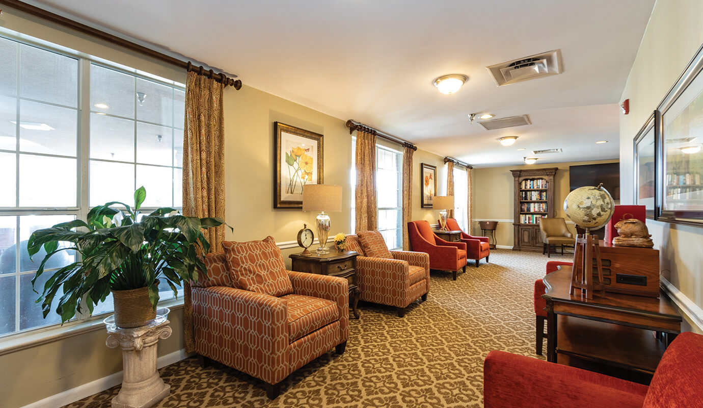 Hotel lounge area with seating, bookcases, tv, and fireplace